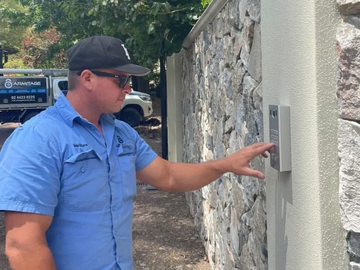 An Armitage Security technician using an intercom panel at a stone entry