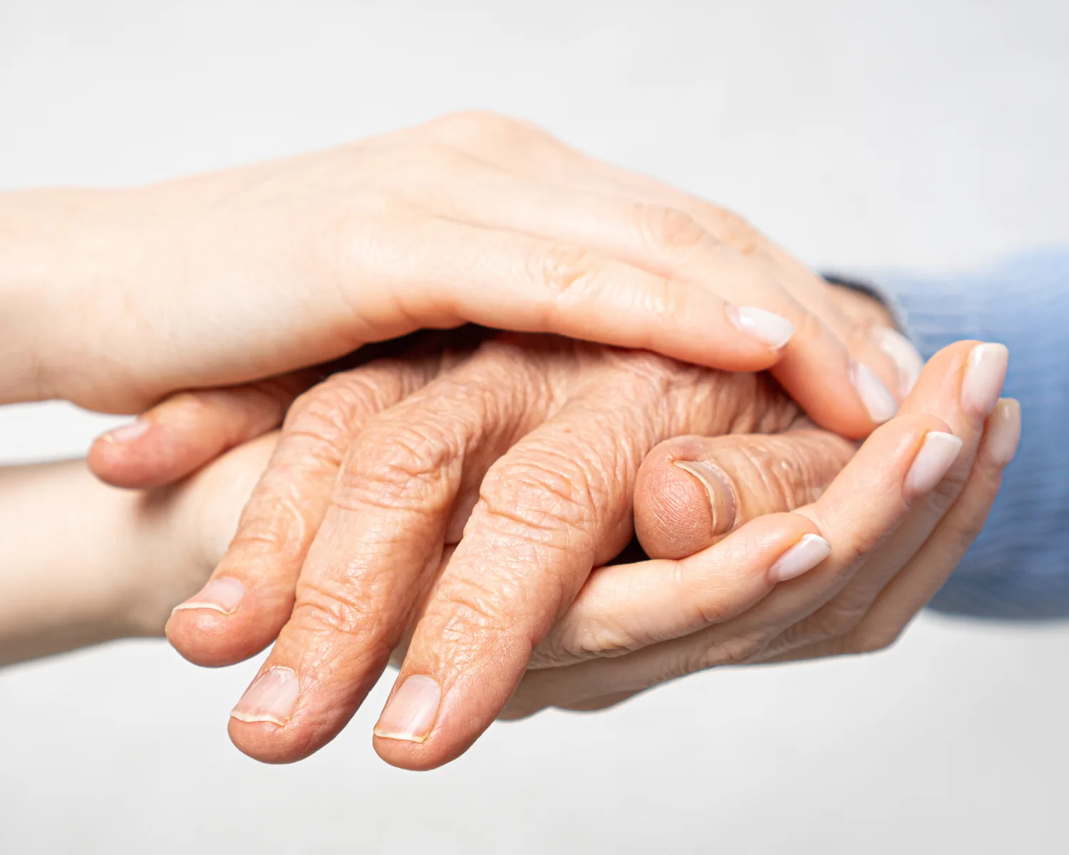 A younger hand resting on an older person's hand