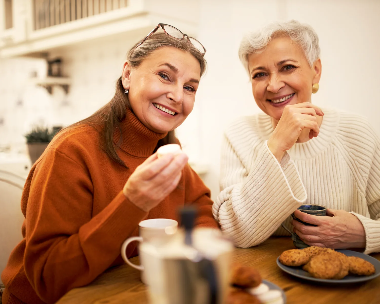 Two older women having coffee together at home